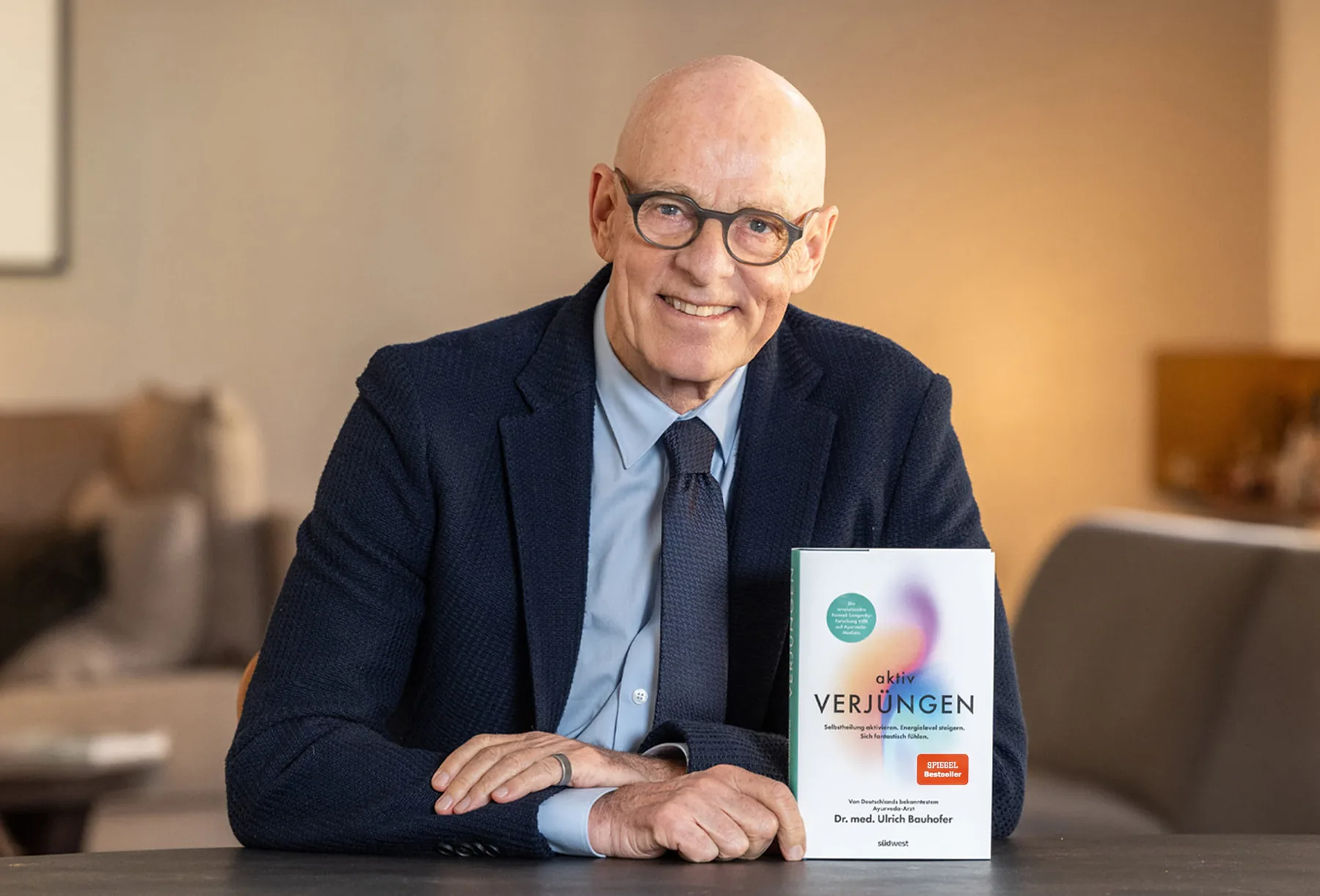 Dr. med. Ulrich Bauhofer holding the aktiv Verjüngen book