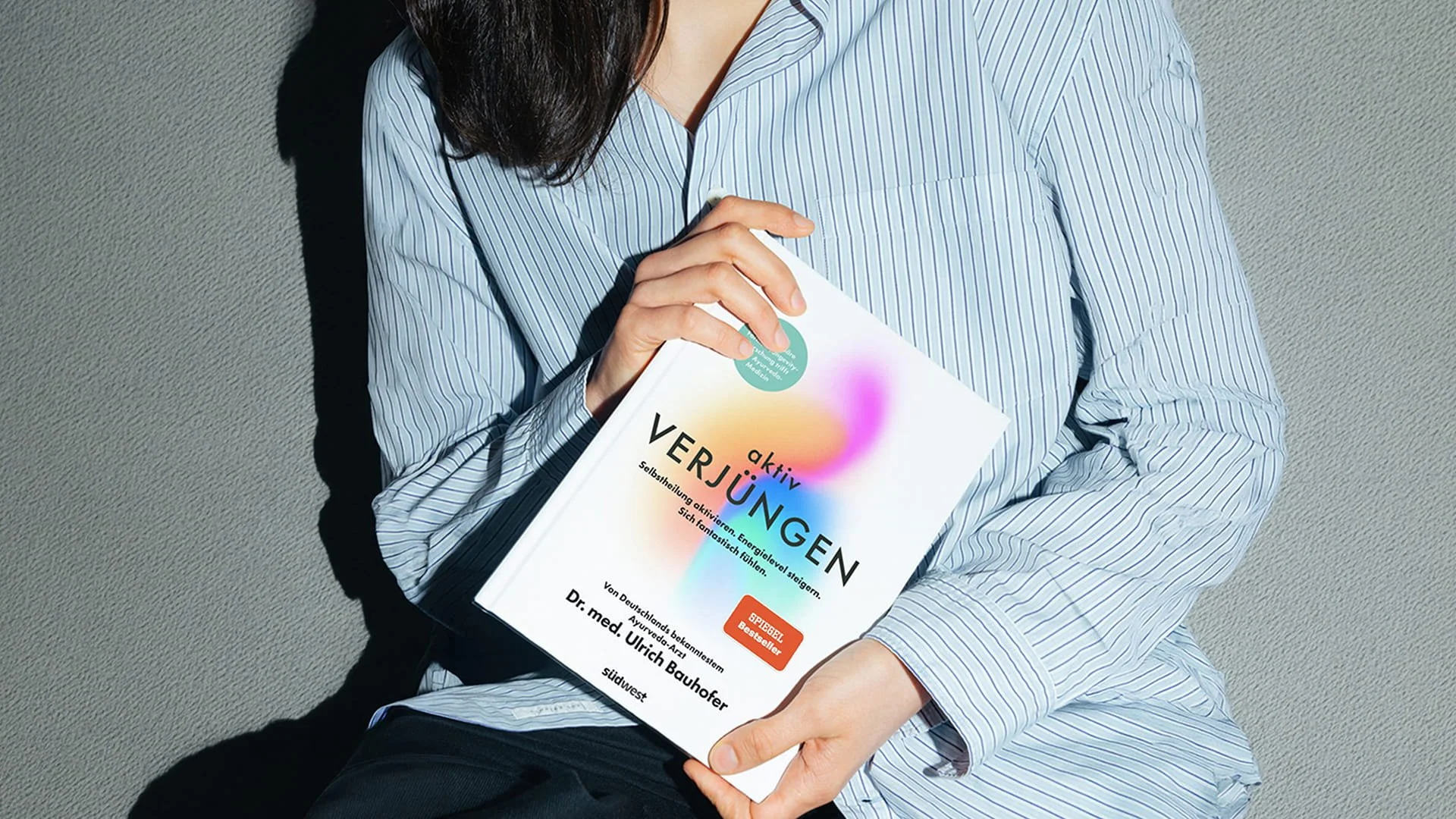 Person holding aktiv Verjüngen by Dr. Ulrich Bauhofer with its colourful book cover
